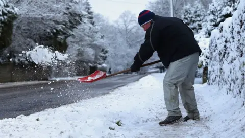 PA wire A man shovels snow in Buxton, Derbyshire