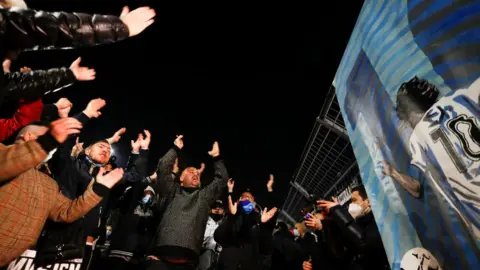 Reuters People hug each other after the death of the Argentine soccer legend Diego Maradona outside San Paolo stadium in Naples, Italy