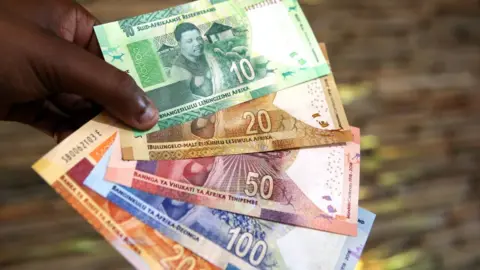 Getty Images A man holding South African rand notes