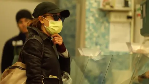 BBC A woman wears a mask in a Bologna market