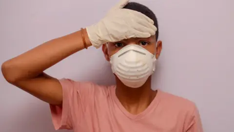 Getty Images A boy in South Africa wearing a face mask and gloves