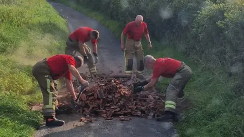 Hicks Gate Fire Station Four firefighters working to clear a large amount of flytipping from a narrow, single track country lane.