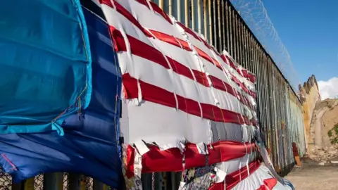 AFP A patchwork representing a US flag hangs on the US-Mexico border in Playas de Tijuana, Baja California State, Mexico, on March 8, 2019