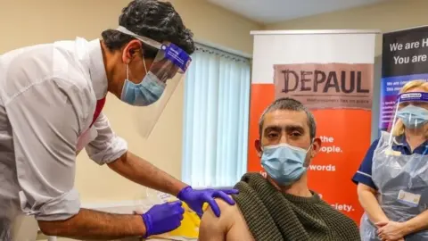 PA Media Lee Ullha receives an injection of a Covid-19 vaccine at the Depaul UK homeless shelter in Oldham