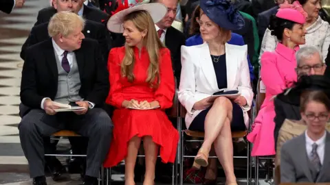 Reuters British Prime Minister Boris Johnson and his wife Carrie Johnson look at each other next to British Foreign Secretary Liz Truss as they attend the National Service of Thanksgiving