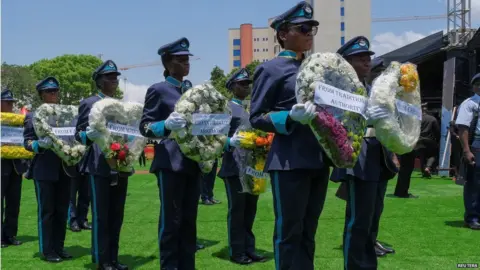 Reuters State employees in uniform hold wreaths of flowers
