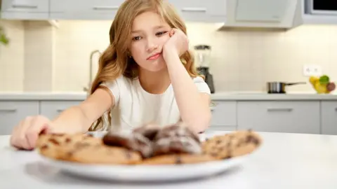 Getty Images Girl looking at a plate of biscuits