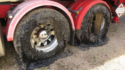 David Anthony / Tablelander Two wheels of a truck coated in tar