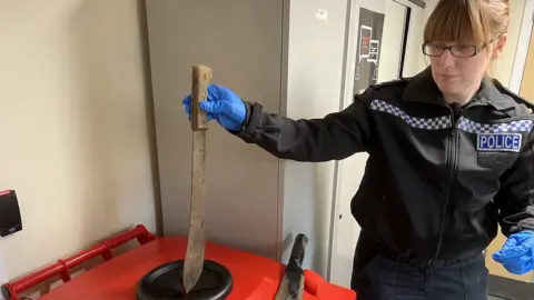 Woman police officer places knife into bin