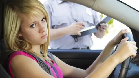 Getty Images Annoyed young woman being given a speeding ticket by a policeman