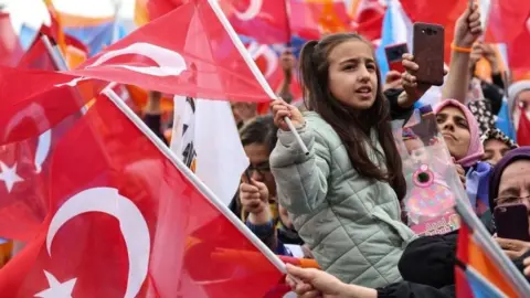 Supporters of Turkish President Recep Tayyip Erdogan wave Turkish flags and cheer during his election campaign rally in Ankara, on April 30, 2023