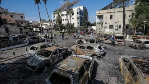 EPA People walk in the courtyard of the Al-Ahli Arab hospital in Gaza City, where hundreds of people were reportedly killed by an explosion (18 October 2023)