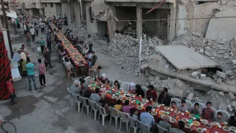 AFP/Getty Images Syrian residents of the rebel-held town of Douma, on the outskirts of the capital Damascus, break their fast with the "iftar" meal on a heavily damaged street on June 18, 2017, during the Muslim holy month of Ramadan.