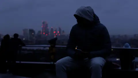 Youth sitting on park bench at dusk