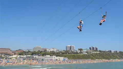 Getty Images People enjoy the zip line ride on the beach at Bournemouth beach on Bank Holiday Monday