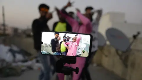 AFP Youths act in front of a mobile phone camera while making a TikTok video on the terrace of their residence in Hyderabad, February 2020