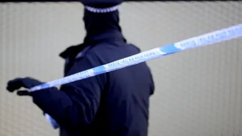 Getty Images A police officer marks a cordon after a fatal stabbing in Hackney on 5 April 5 2018 in London