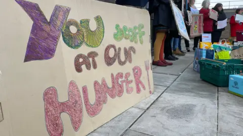 Shaun Whitmore/BBC Protesters to the scrapping of the scheme outside County Hall in Norwich