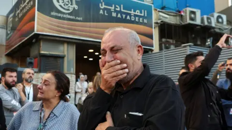 Reuters Colleagues of the two Al Mayadeen journalists, who Lebanese officials say were killed by an Israeli strike in southern Lebanon, mourn outside the channel's office in Beirut, Lebanon (21 November 2023)