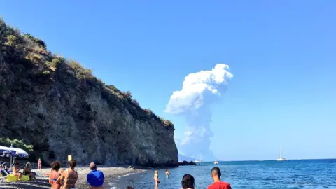Carmelo Saia Tourists look on at an explosion in the distance
