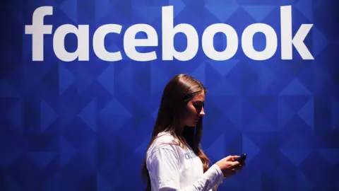 PA Media Woman walking past Facebook logo