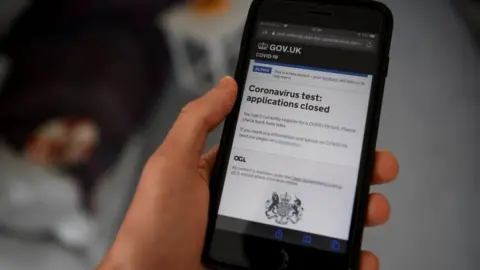 Getty Images A mobile phone shows the government's coronavirus test application website