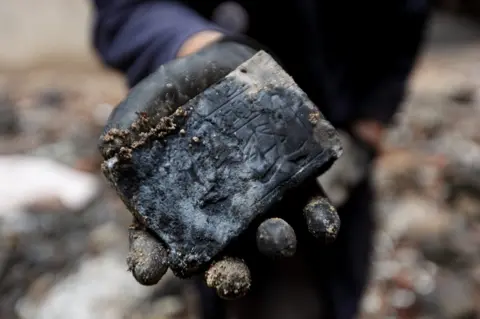 Douglas Engle Close up of a hand holding a fragment of a stele