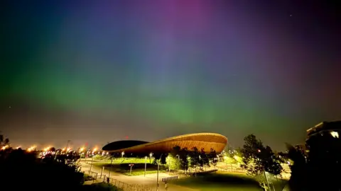 Tom View of green, blue and pink northern lights above Stratford's Olympic Park and London Stadium