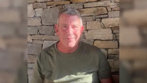 Provided A man with grey hair, a tan, and a green top