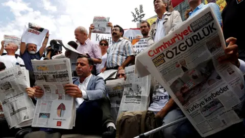 Reuters People reading newspapers in protest