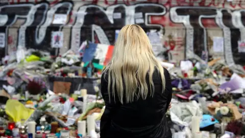 Getty Images A woman stands in front of a makeshift memorial