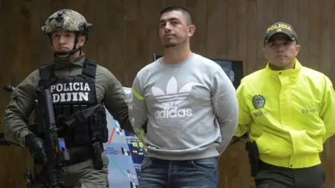 In this file photo taken on April 11, 2017 Colombian Police officers escort Ecuadorean Washington Prado Alava aka "Gerald" (C), during a press conference at the police headquarters in Bogota, Colombia.