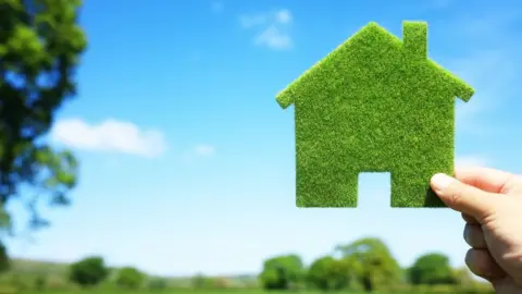 Getty Images Hand holding cut out of house made of grass