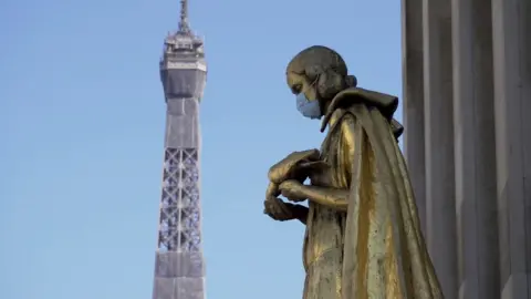 Masked statue with Eiffel Tower in background