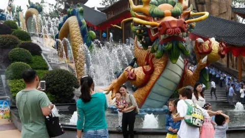 EPA Visitors take photos beside a dragon fountain at an outdoor theme park of the newly-opened Wanda Cultural Tourism City or "Wanda City" in the eastern city of Nanchang in Jiangxi Province, China, 28 May 2016