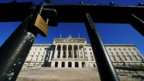 PA Media A lock on a gate outside Parliament Buildings at Stormont