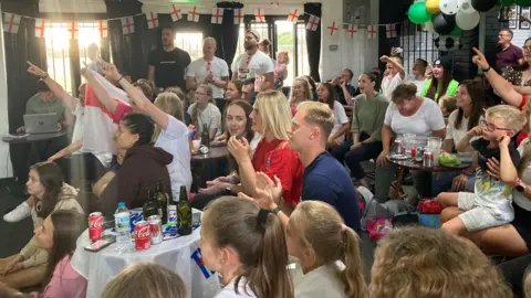 Tom Williams/BBC Fan celebrating England's win at the clubhouse at North Walsham Football Club