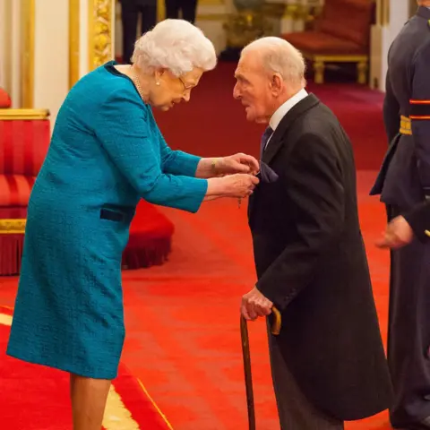 PA The Queen presents George "Johnny" Johnson with his MBE