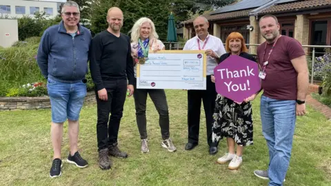 St Elizabeth Hospice Wendy Kelway and her family presenting a cheque for £10,000 to the St Elizabeth Hospice team