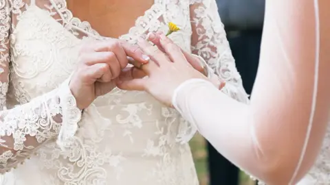 Getty Images/Geoff Goldswain Brides exchanging wedding rings