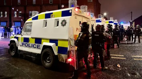 PA Media PSNI officers and Land Rovers on the nationalist side of the Springfield Road in Belfast after dispersing people from the area, following further unrest. Picture date: Wednesday April 7, 2021