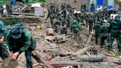 AFP Rescuers look for survivors in the rubble of damaged buildings in China's eastern Zhejiang province after a landslide caused by torrential rain from Typhoon Lekima on 10 August.