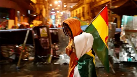 Reuters People walk past a barricade during a protest against Bolivia's President Evo Morales in La Paz, November 10, 2019