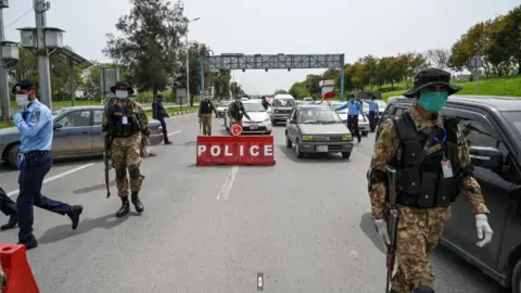 Getty Images Security personnel wearing facemasks check commuters at a checkpoint of the city's entrance during a government-imposed nationwide lockdown as a preventive measure against the COVID-19 coronavirus in Islamabad