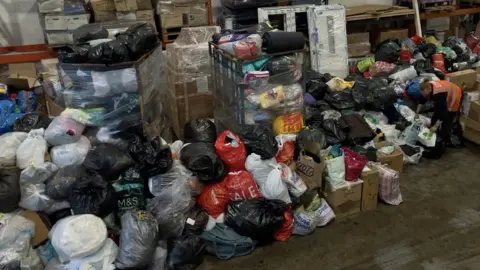 BBC Piles of donations in bags and boxes at the Island Express warehouse