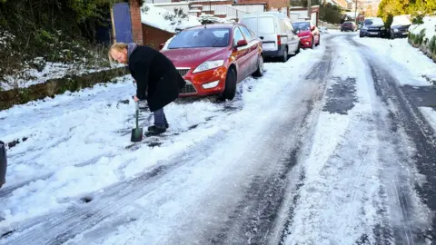 PA A man clears snow to try free his car