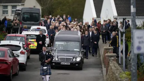 PA Media A piper plays as the hearse carrying Martin McGill, 49, arrives at St Michael's Church, Creeslough, for his funeral mass. Martin died following an explosion at Applegreen service station in the village of Creeslough in Co Donegal on Friday