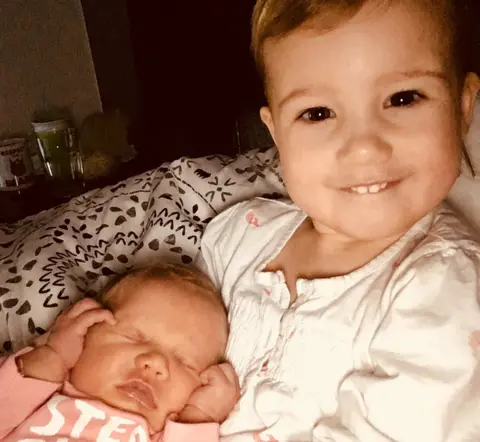 Charlotte Lomas Amelia cuddling her sister Eliza on the baby's first morning at home