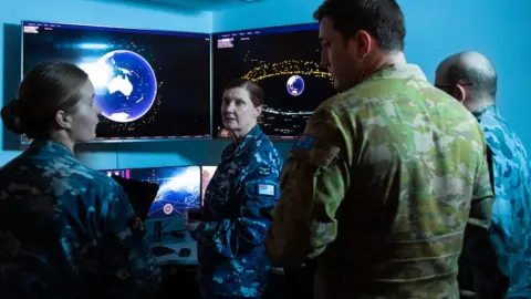 Australia Government Department of Defence Members of Space Command talking with screens in the back