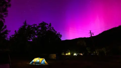 Getty Images Northern lights or aurora borealis illuminate the night sky over a camper's tent north of San Francisco in Middletown, California